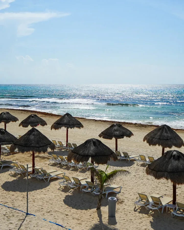 Playa de arena blanca con palapas frente al Caribe