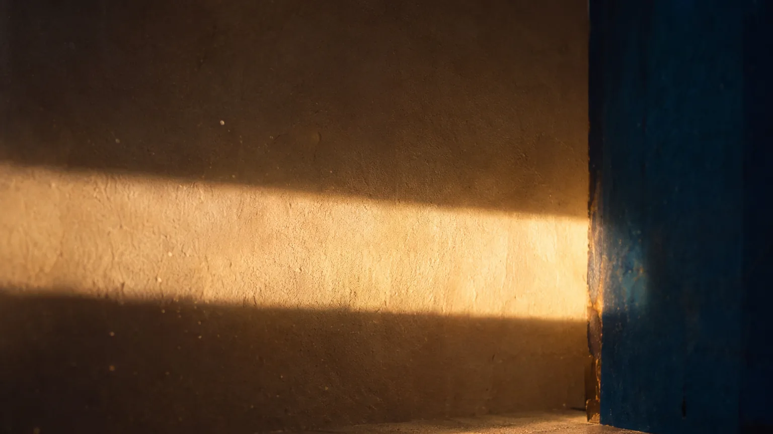 Muro en luz de tarde contra un plano azul